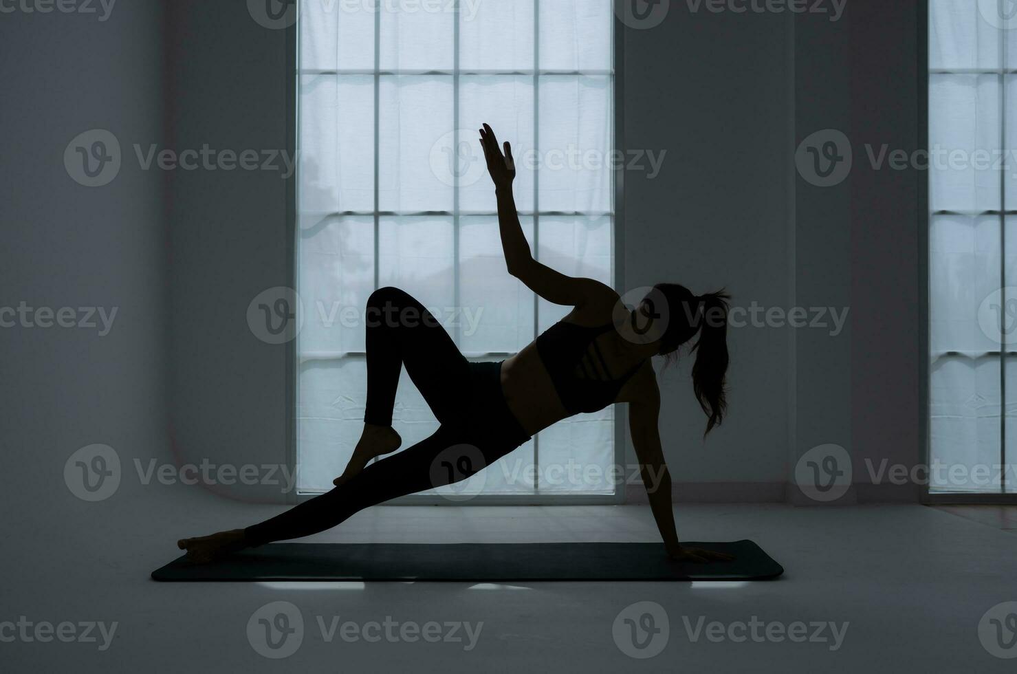 Silhouette of a young woman practicing yoga in the room. photo