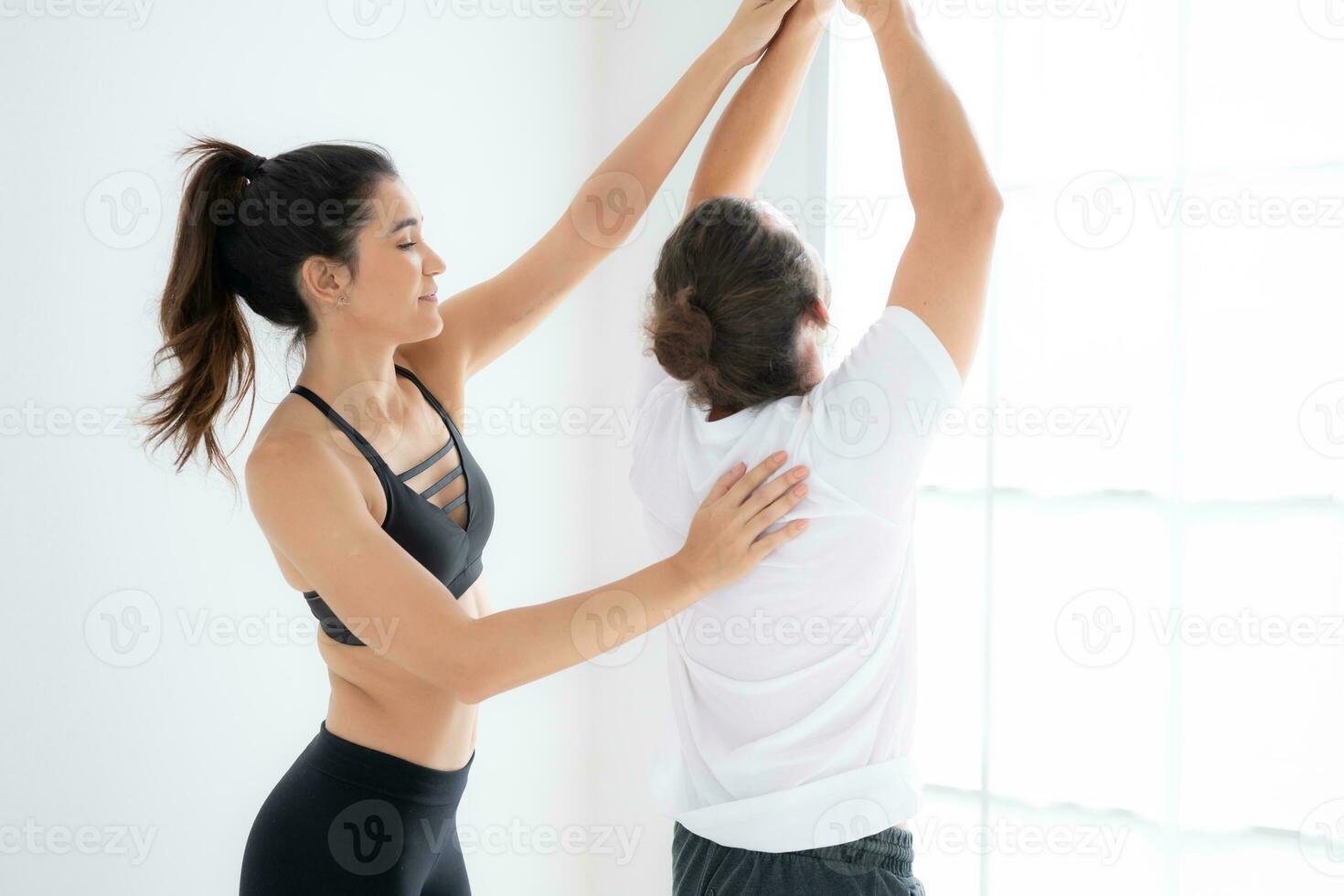 Young couple practicing yoga in a white room of studio. photo