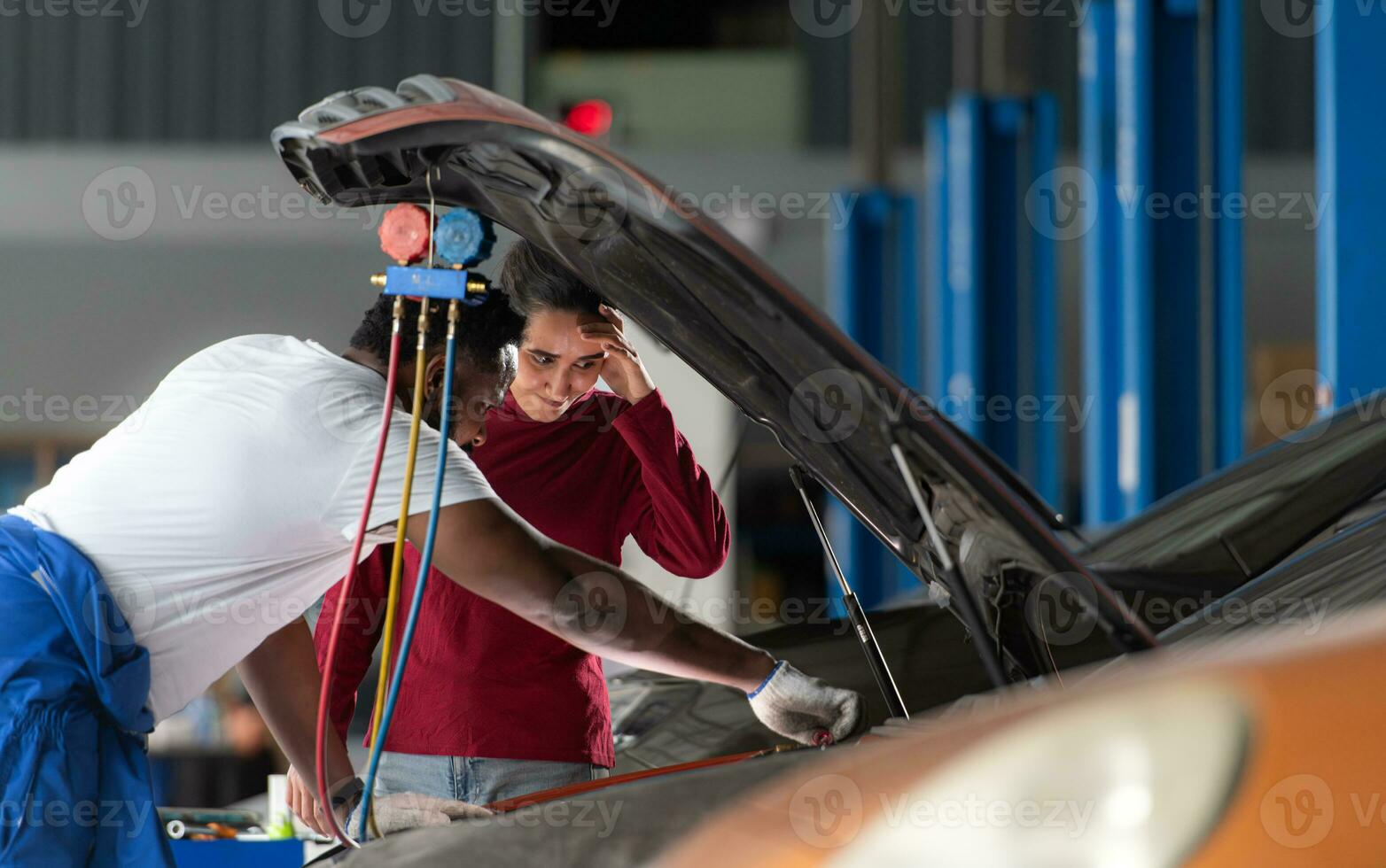 Car mechanic working in an auto repair shop explain to customer after inspecting the operation of the car's air conditioner and refrigerant photo