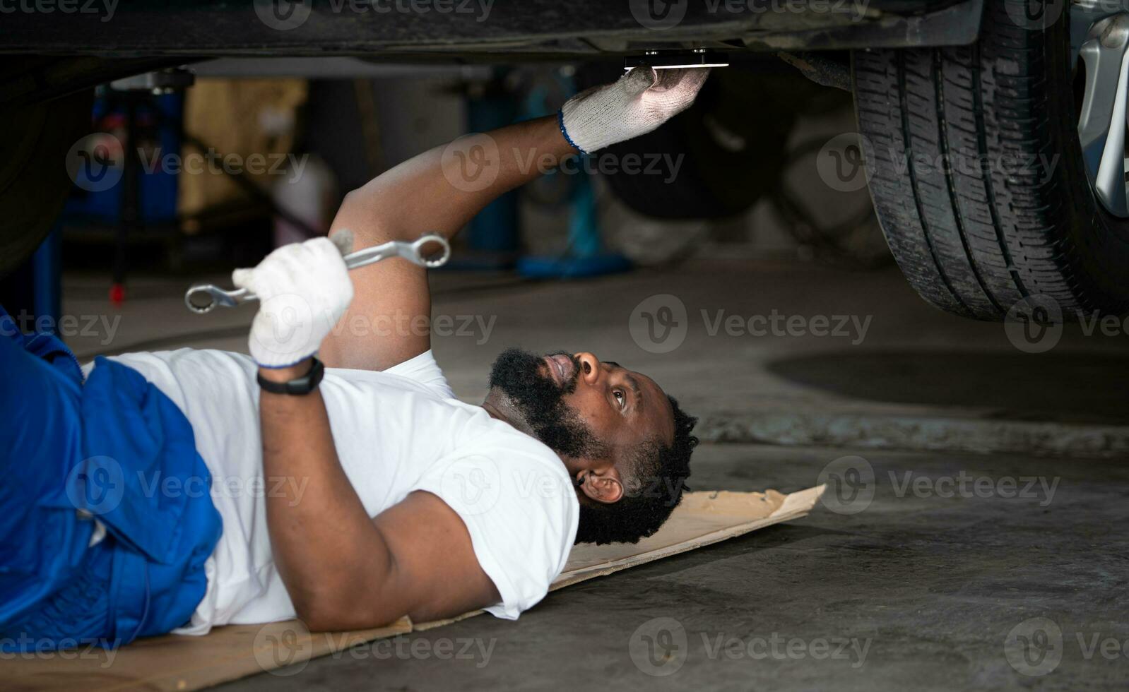 Car mechanic working in an auto repair shop, Check the operation of the engine of under the car that comes in for repairs at the auto repair shop. photo