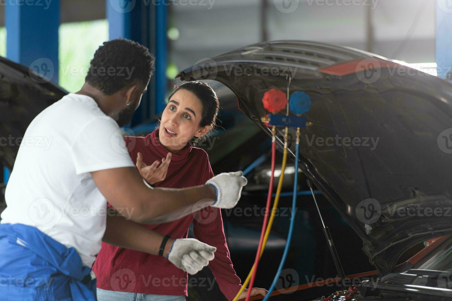 Car mechanic working in an auto repair shop explain to customer after inspecting the operation of the car's air conditioner and refrigerant photo