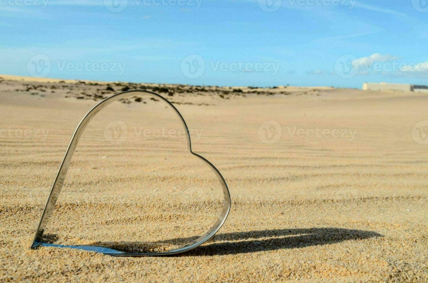 a heart shaped metal object in the sand photo