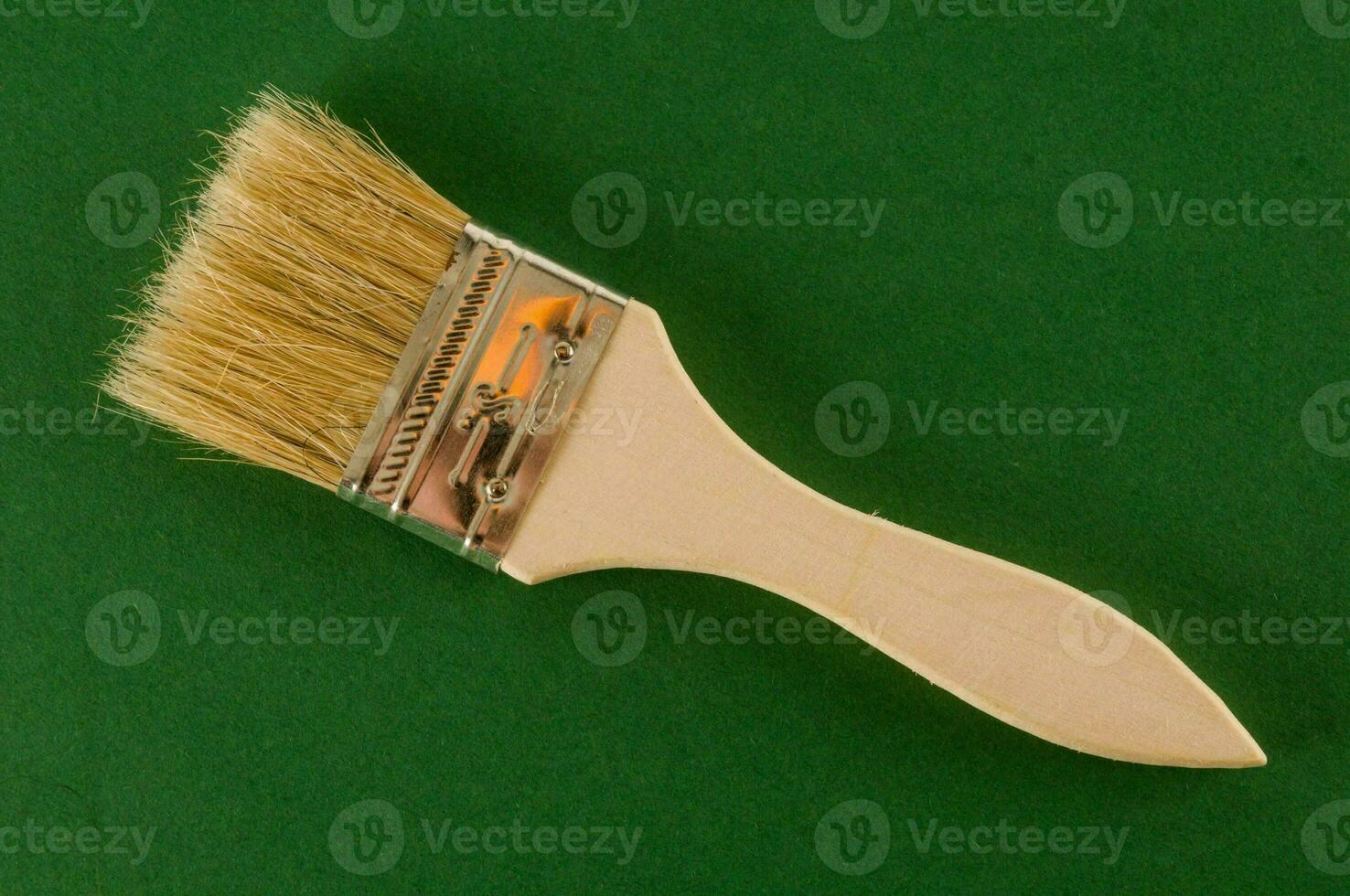 a brush with a wooden handle on a green surface photo