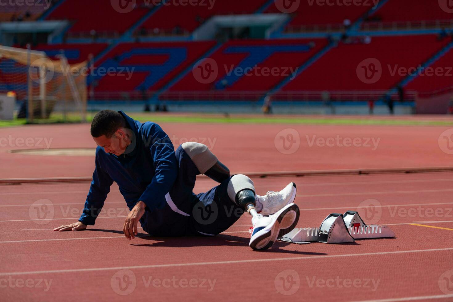 Disabled athletic man stretching and warming up before running on stadium track photo