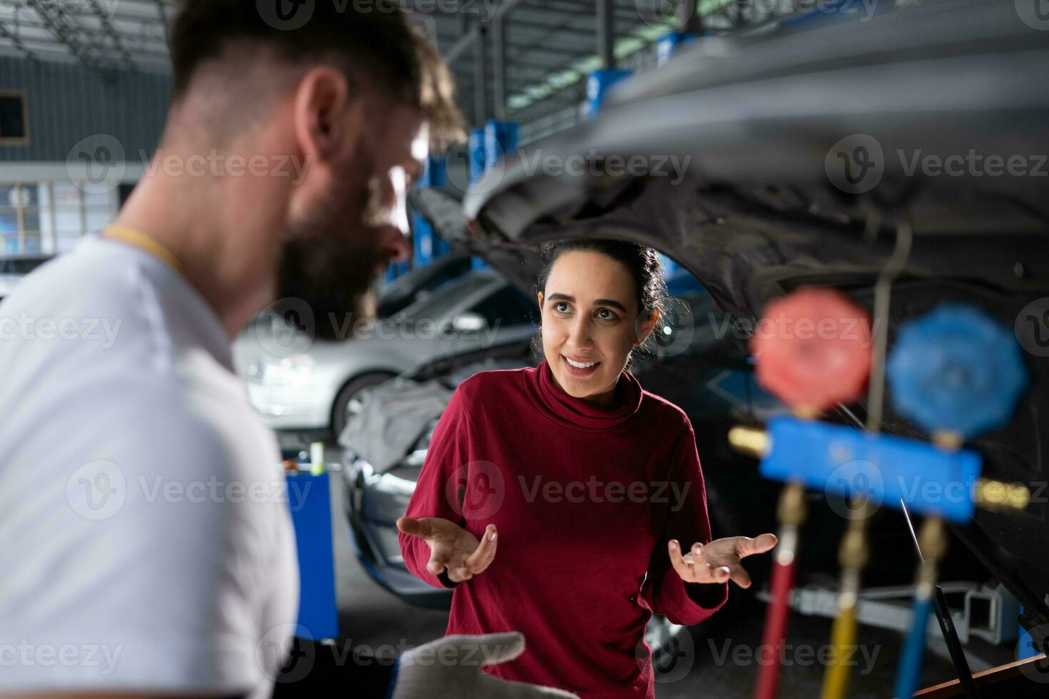 Car mechanic working in an auto repair shop explain to customer after inspecting the operation of the car's air conditioner and refrigerant photo