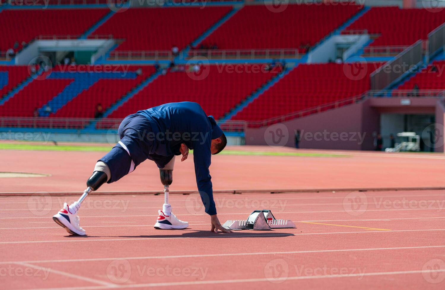 Disabled athletic man stretching and warming up before running on stadium track photo