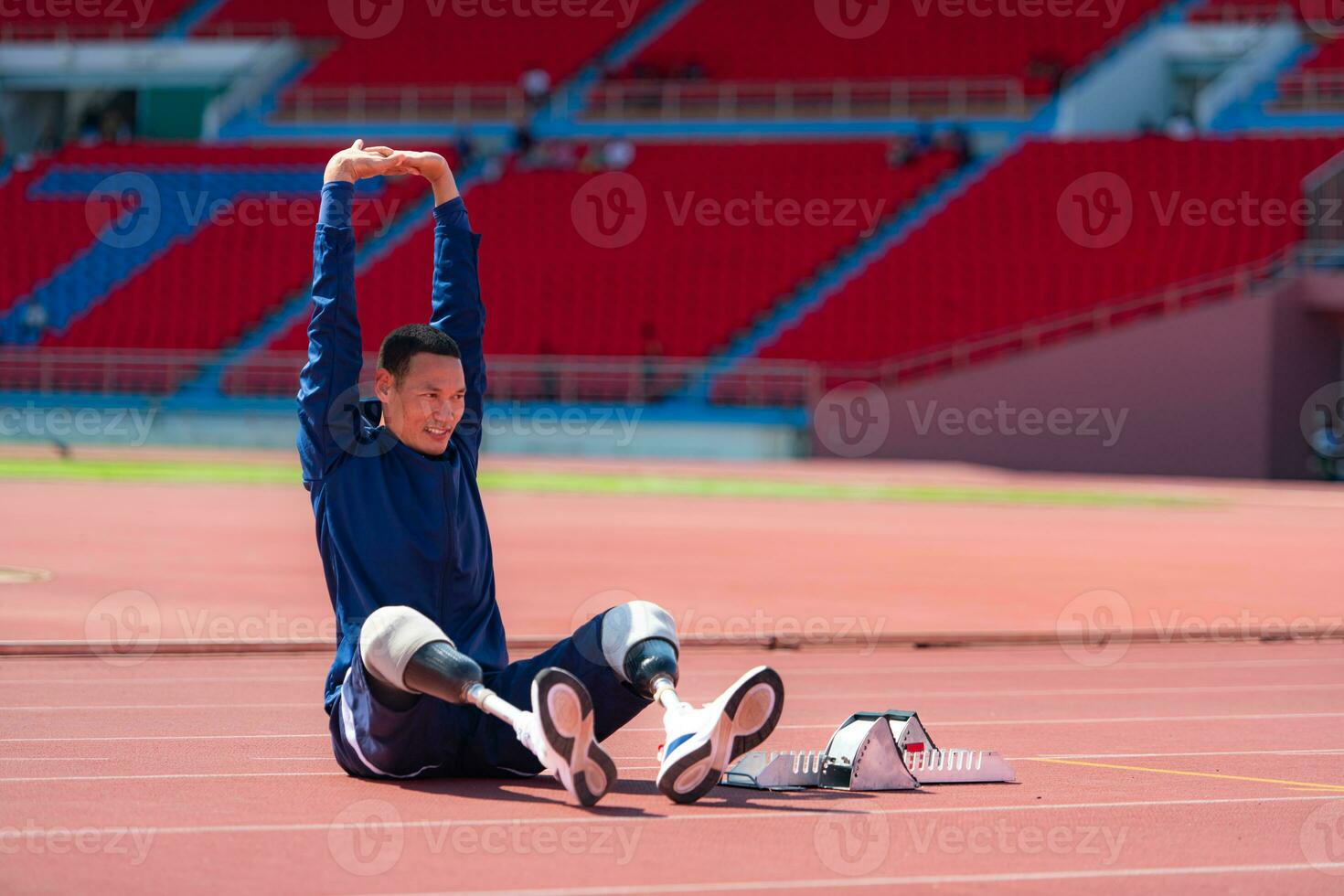 Disabled athletic man stretching and warming up before running on stadium track photo