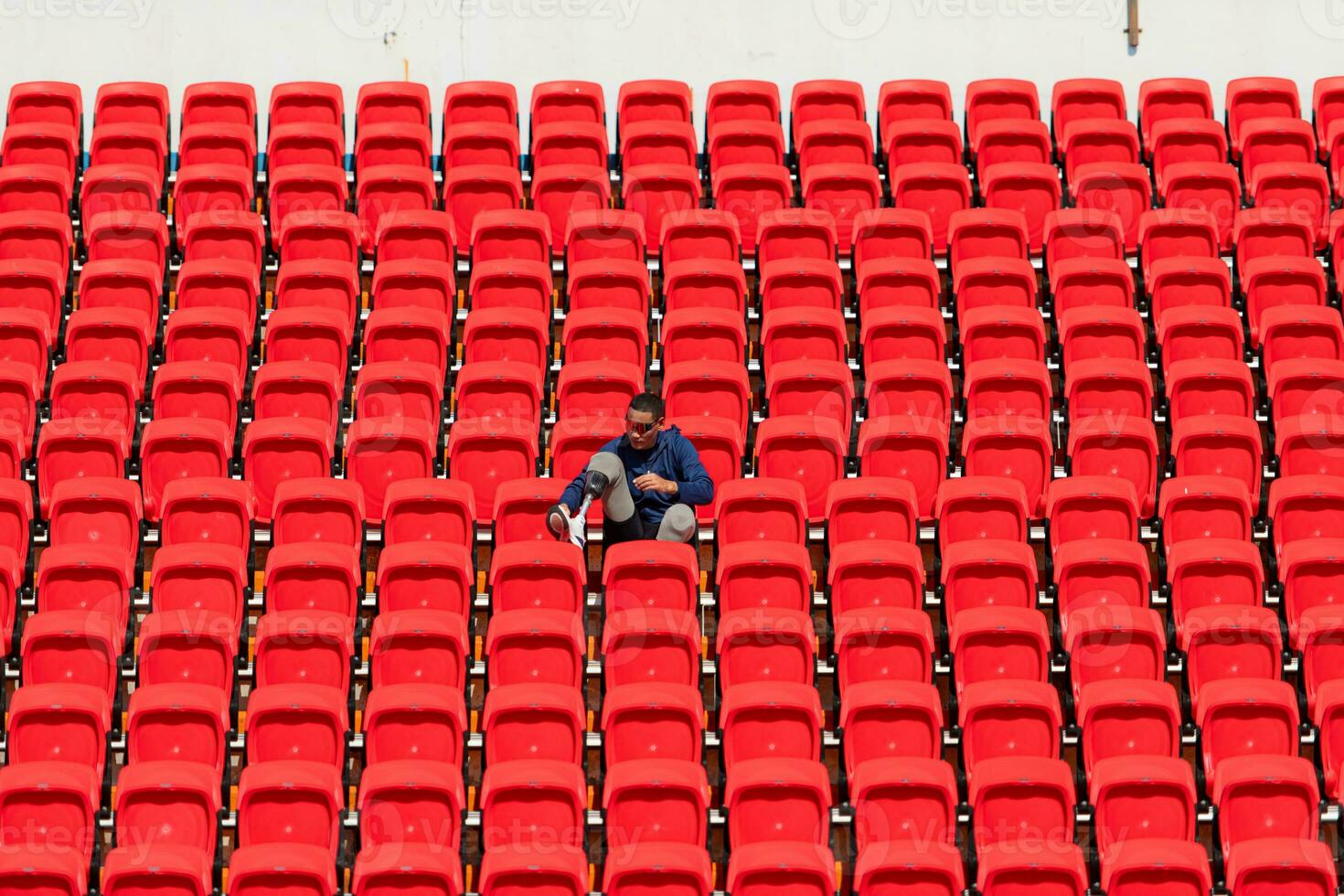 Disabled athletes in a blue shirt sitting on the red seats at the stadium, Prepare for running training. photo