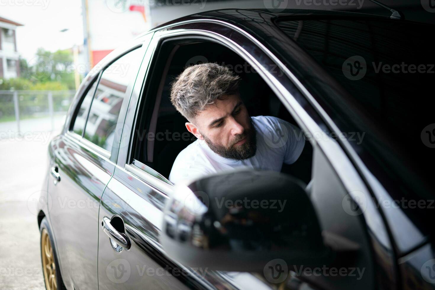 A young man vehicle technician working inside a car at an auto repair shop. photo