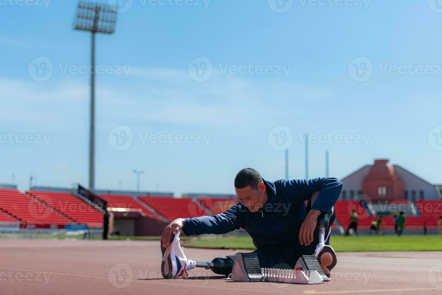 Disabled athletic man stretching and warming up before running on stadium track photo