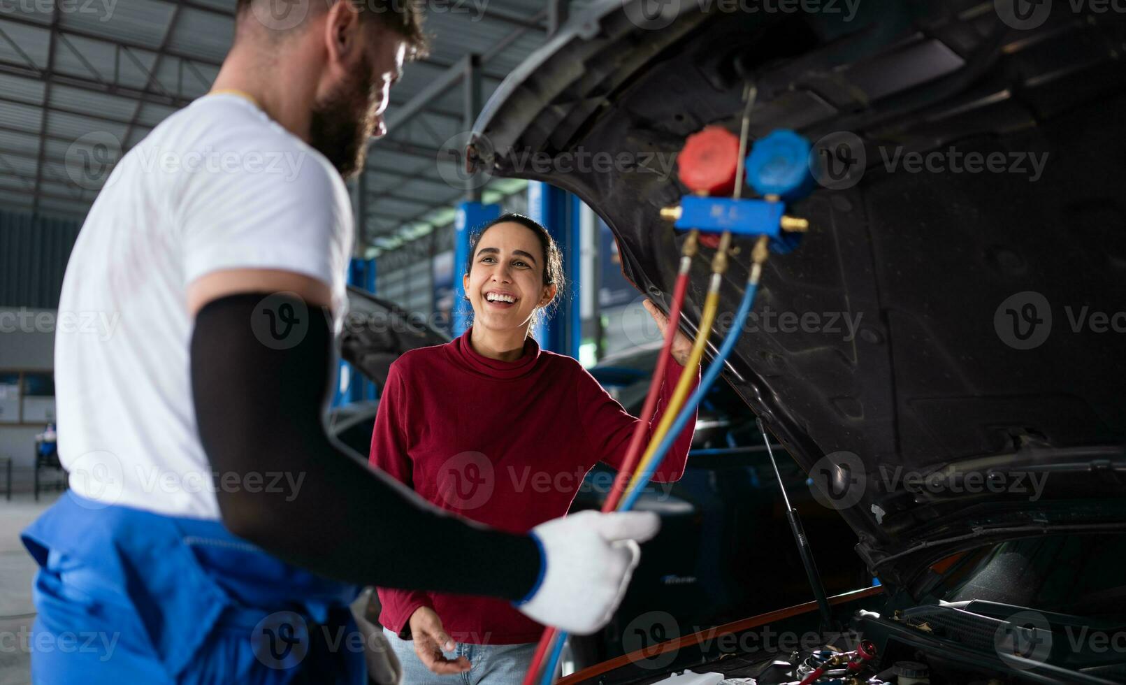 Car mechanic working in an auto repair shop explain to customer after inspecting the operation of the car's air conditioner and refrigerant photo