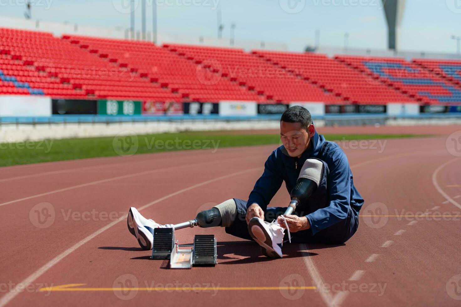 discapacitado atlético hombre extensión y calentamiento arriba antes de corriendo en estadio pista foto