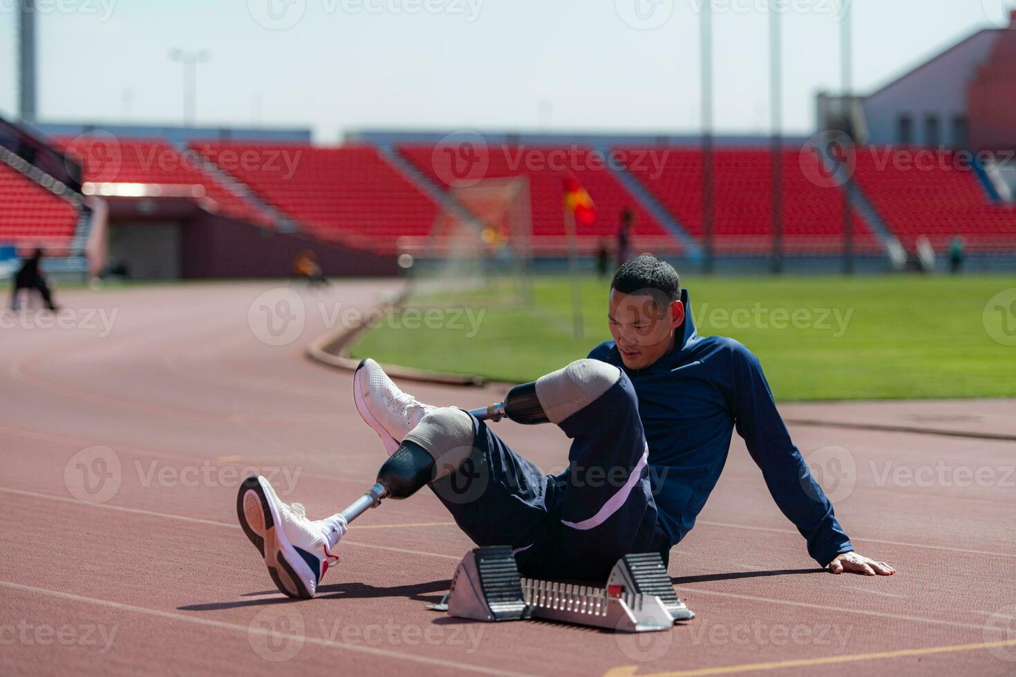 discapacitado atlético hombre extensión y calentamiento arriba antes de corriendo en estadio pista foto