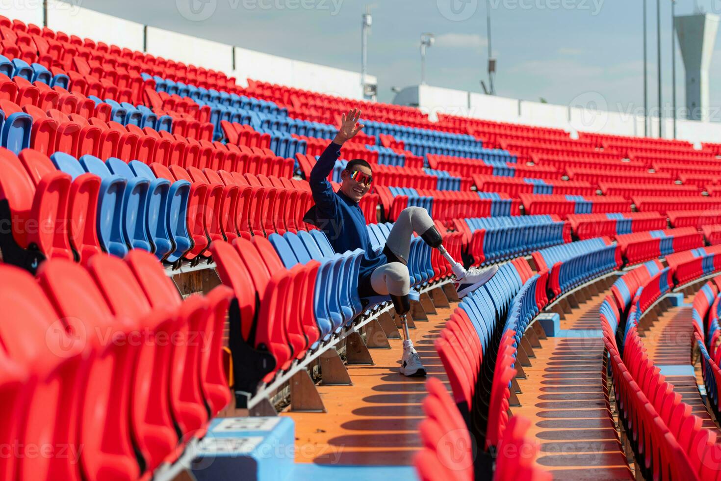 Disabled athletes prepare their bodies on amphitheater in a sports arena on a sunny day before entering a short-distance running competition photo