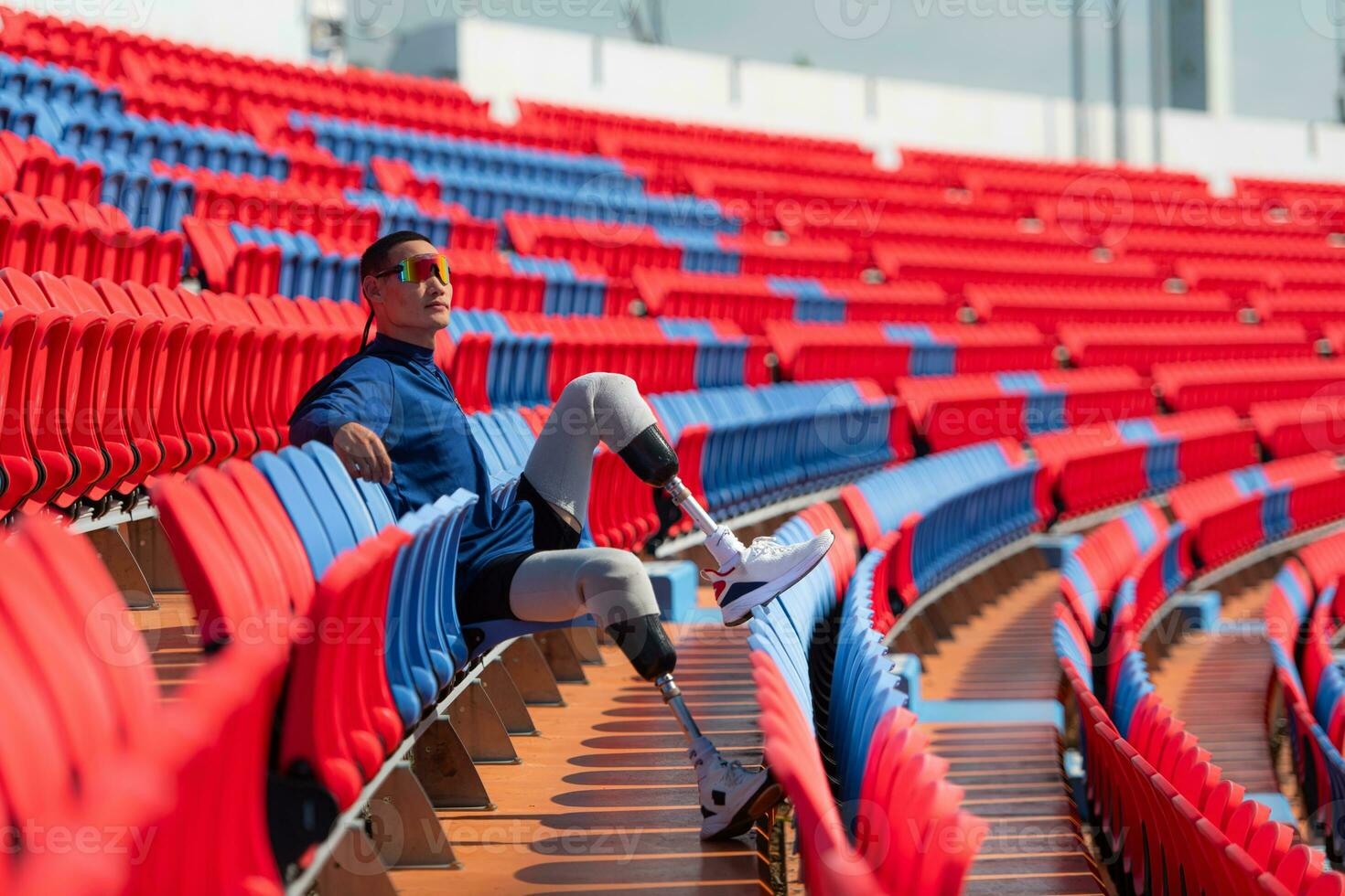 Disabled athletes prepare their bodies on amphitheater in a sports arena on a sunny day before entering a short-distance running competition photo