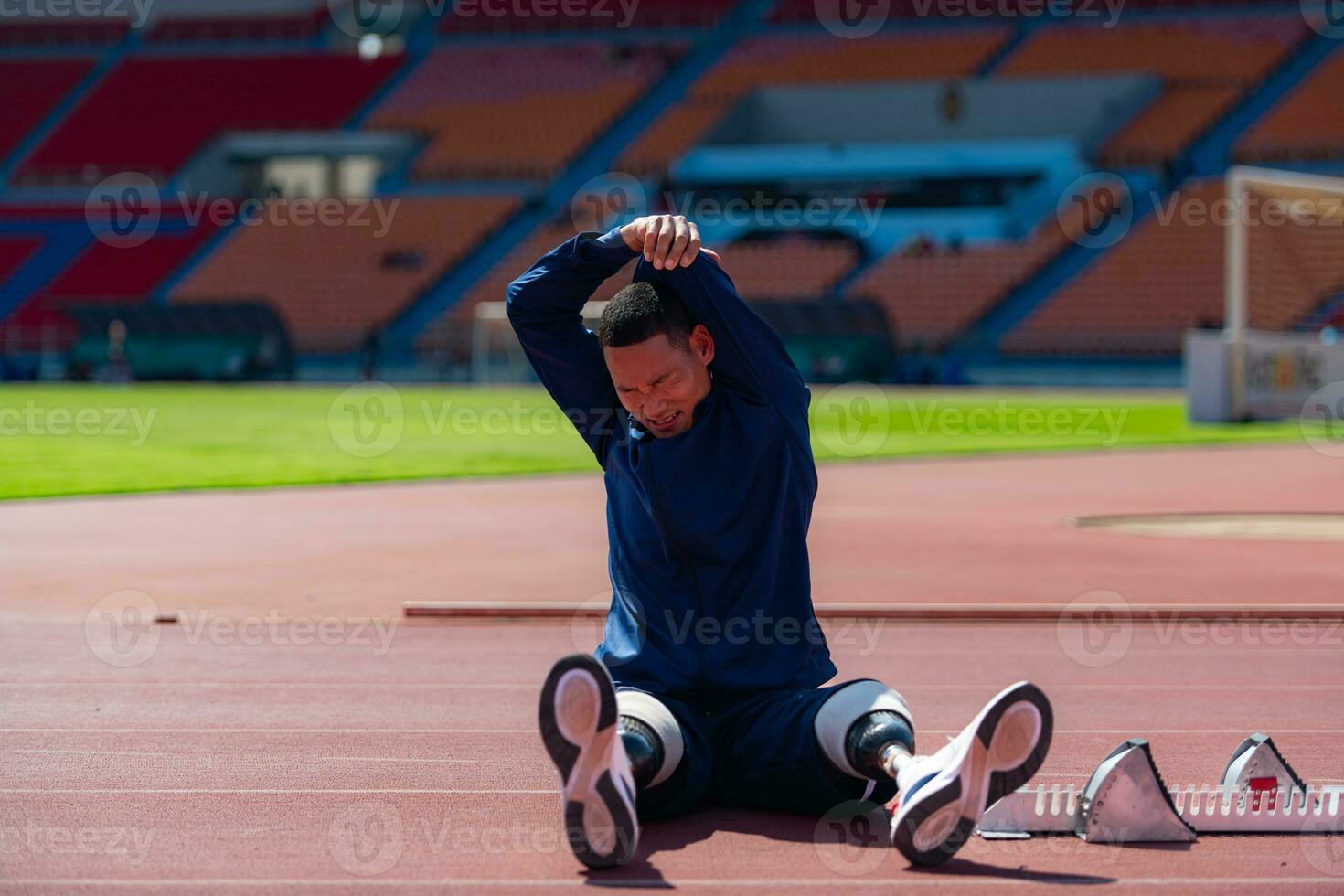 discapacitado atlético hombre extensión y calentamiento arriba antes de corriendo en estadio pista foto