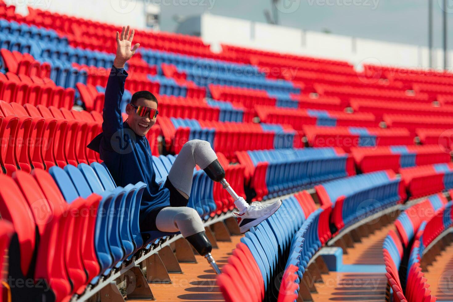 Disabled athletes prepare their bodies on amphitheater in a sports arena on a sunny day before entering a short-distance running competition photo