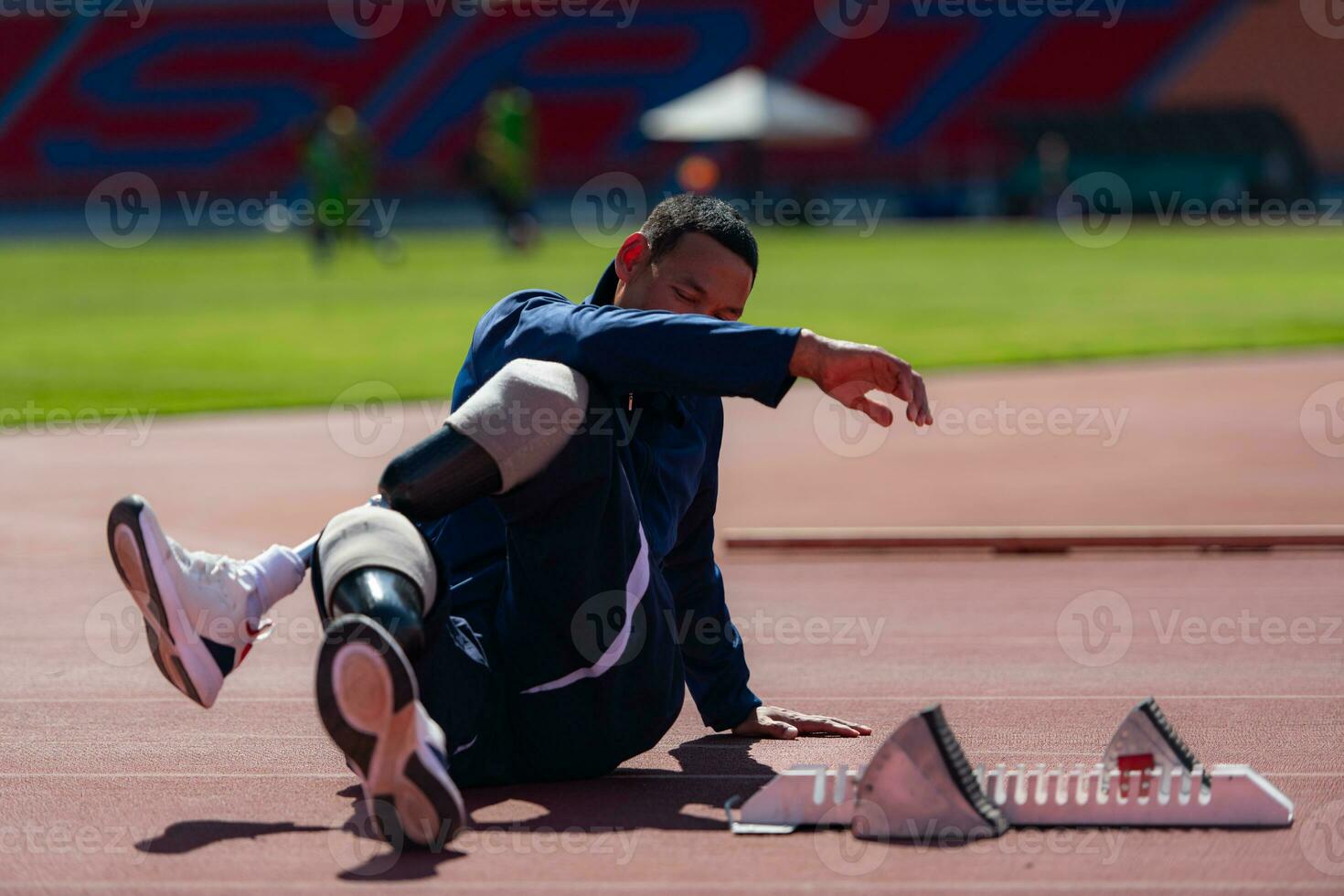 discapacitado atlético hombre extensión y calentamiento arriba antes de corriendo en estadio pista foto