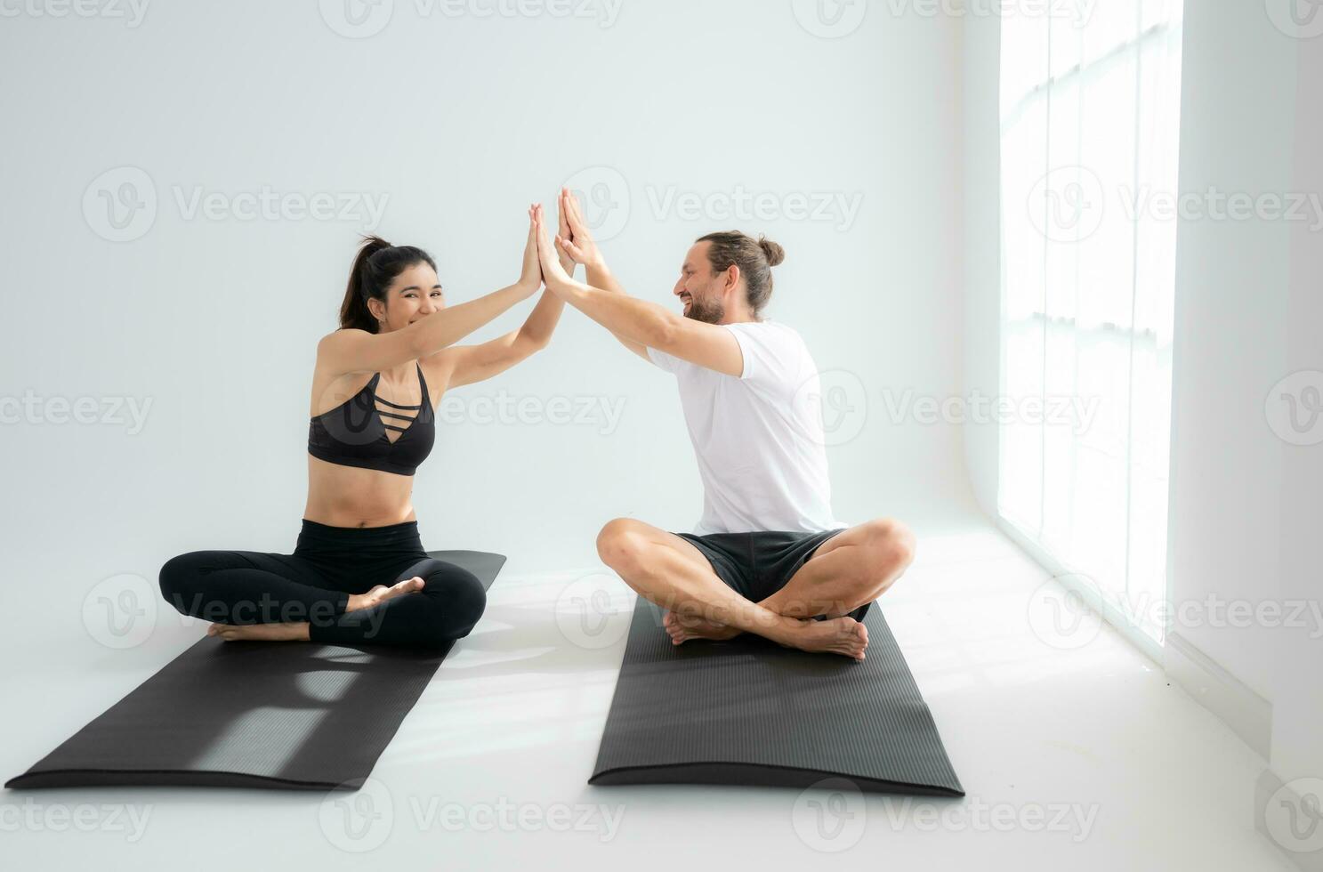 Young couple practicing yoga in a white room of studio. photo