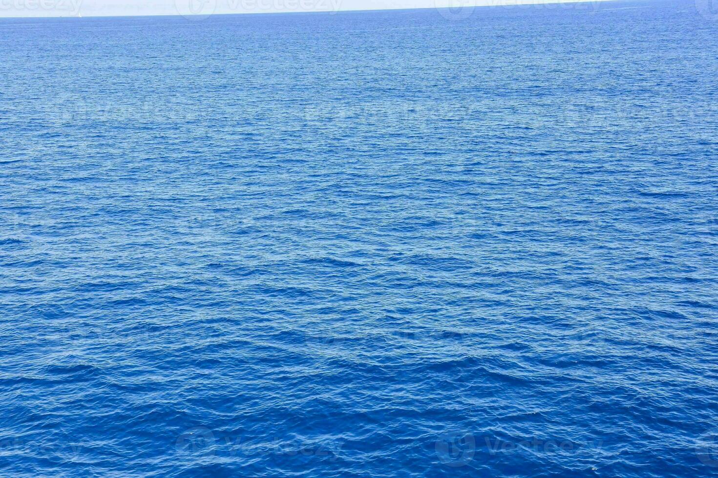 the ocean is blue and calm with a boat in the distance photo