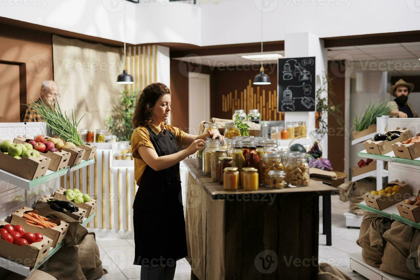 Vendor arranging products sold in bulk in zero waste store, minimizing plastic usage, creating positive environmental impact. Seller preparing ethically sourced pantry staples for incoming customers photo