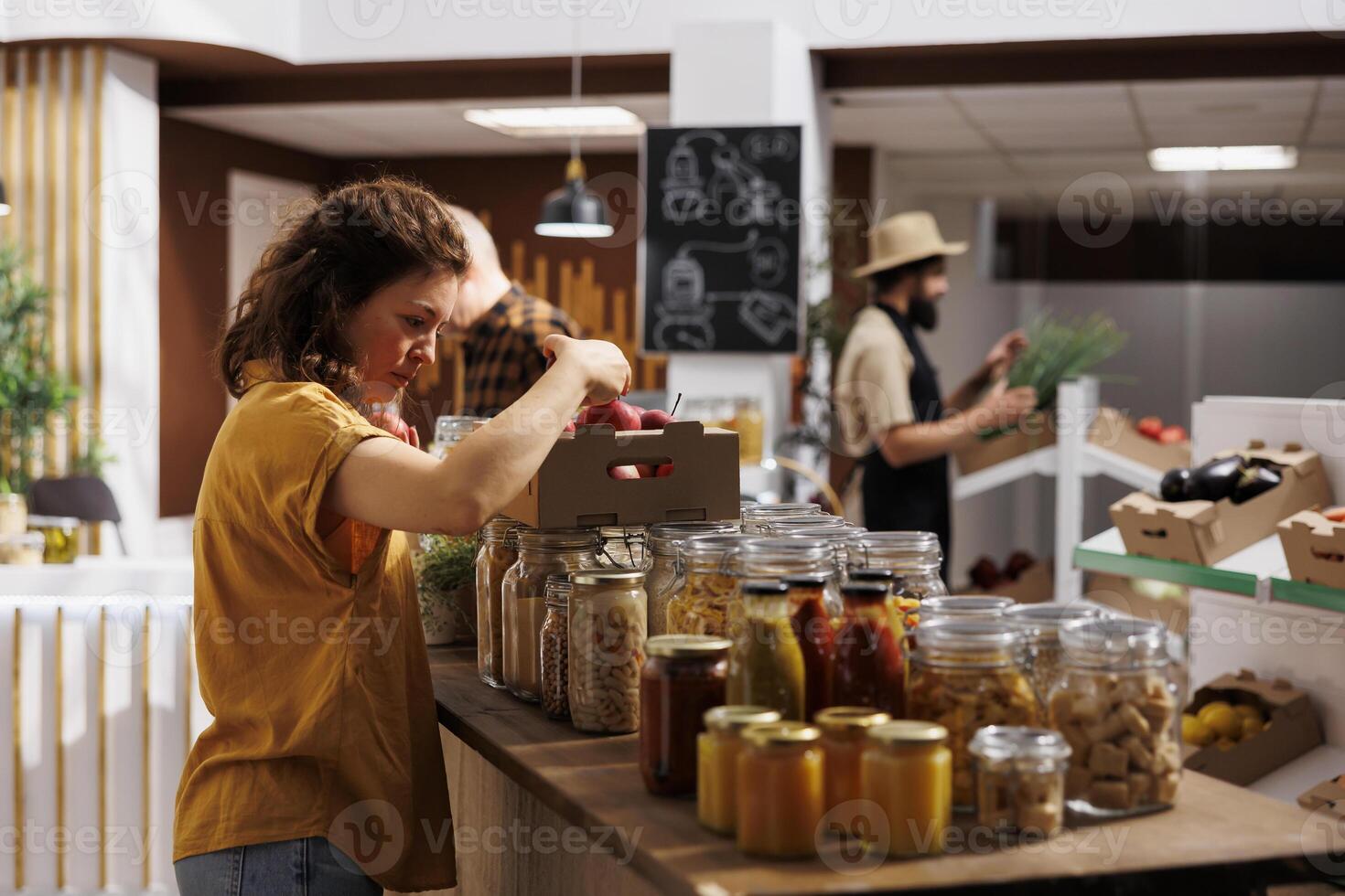 Healthy living woman in zero waste shop looking to buy freshly handpicked apples and other fruits. Customer shopping for chemicals free groceries in local neighborhood store photo