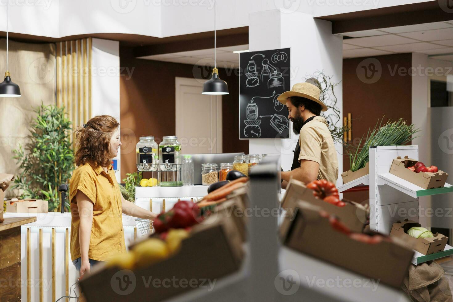 Man and woman in zero waste store filling shopping baskets with healthy locally sourced vegetables. Environmentally responsible clients buying organic pesticides free food from local neighborhood shop photo