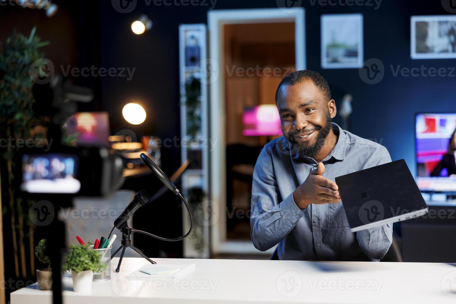 African american internet show host using professional camera and microphone to film content about best gaming laptops of the year. Tech engineer recording notebook digital device review photo