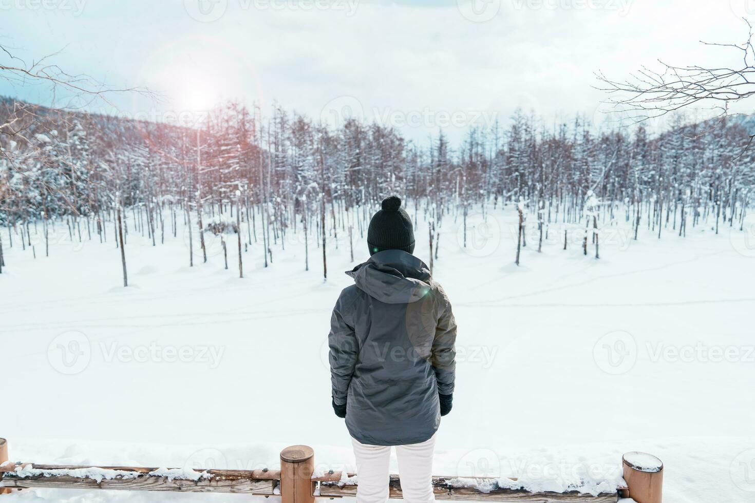 Woman tourist Visiting in Biei, Traveler in Sweater sightseeing Blue Pond with Snow in winter. landmark and popular for attractions in Hokkaido, Japan. Travel and Vacation concept photo