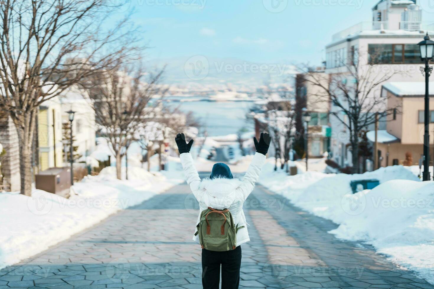 Woman tourist Visiting in Hakodate, Traveler in Sweater sightseeing Hachiman Zaka Slope with Snow in winter. landmark and popular for attractions in Hokkaido, Japan. Travel and Vacation concept photo