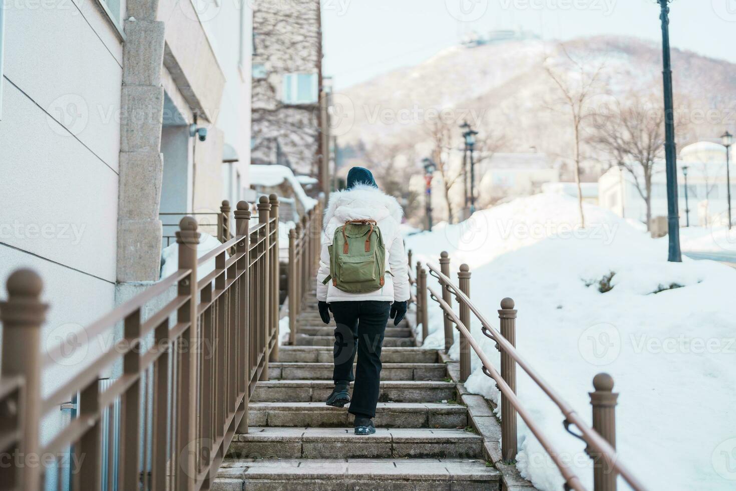 Woman tourist Visiting in Hakodate, Traveler in Sweater sightseeing Hachiman Zaka Slope with Snow in winter. landmark and popular for attractions in Hokkaido, Japan. Travel and Vacation concept photo