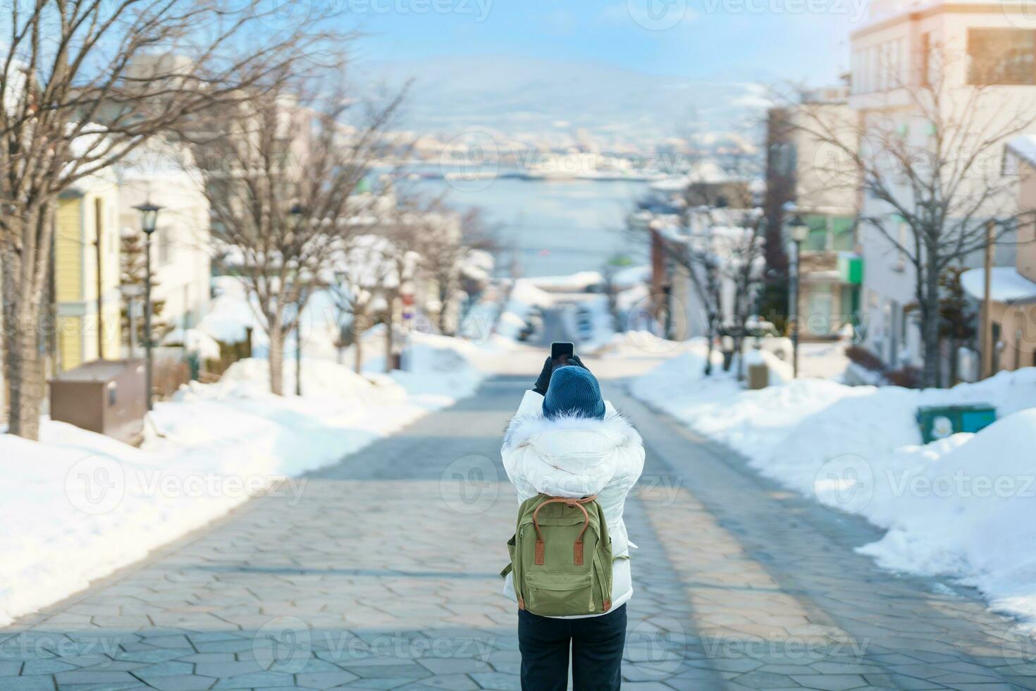 Woman tourist Visiting in Hakodate, Traveler in Sweater sightseeing Hachiman Zaka Slope with Snow in winter. landmark and popular for attractions in Hokkaido, Japan. Travel and Vacation concept photo