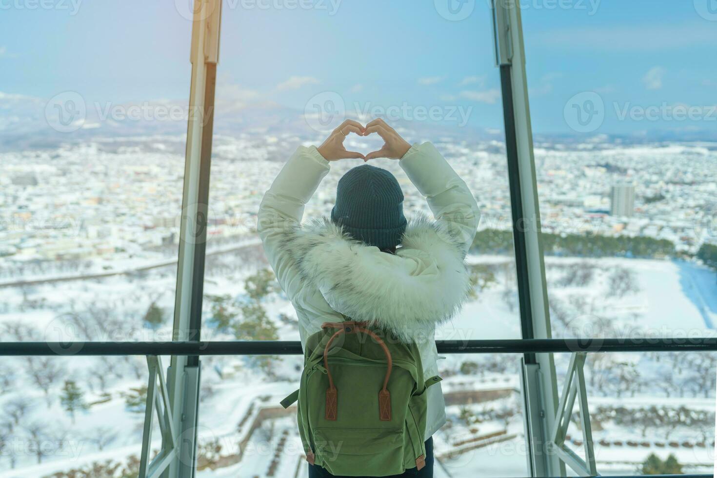 Woman tourist Visiting in Hakodate, Traveler in Sweater sightseeing view from Goryokaku Tower with Snow in winter. landmark and popular for attractions in Hokkaido, Japan.Travel and Vacation concept photo