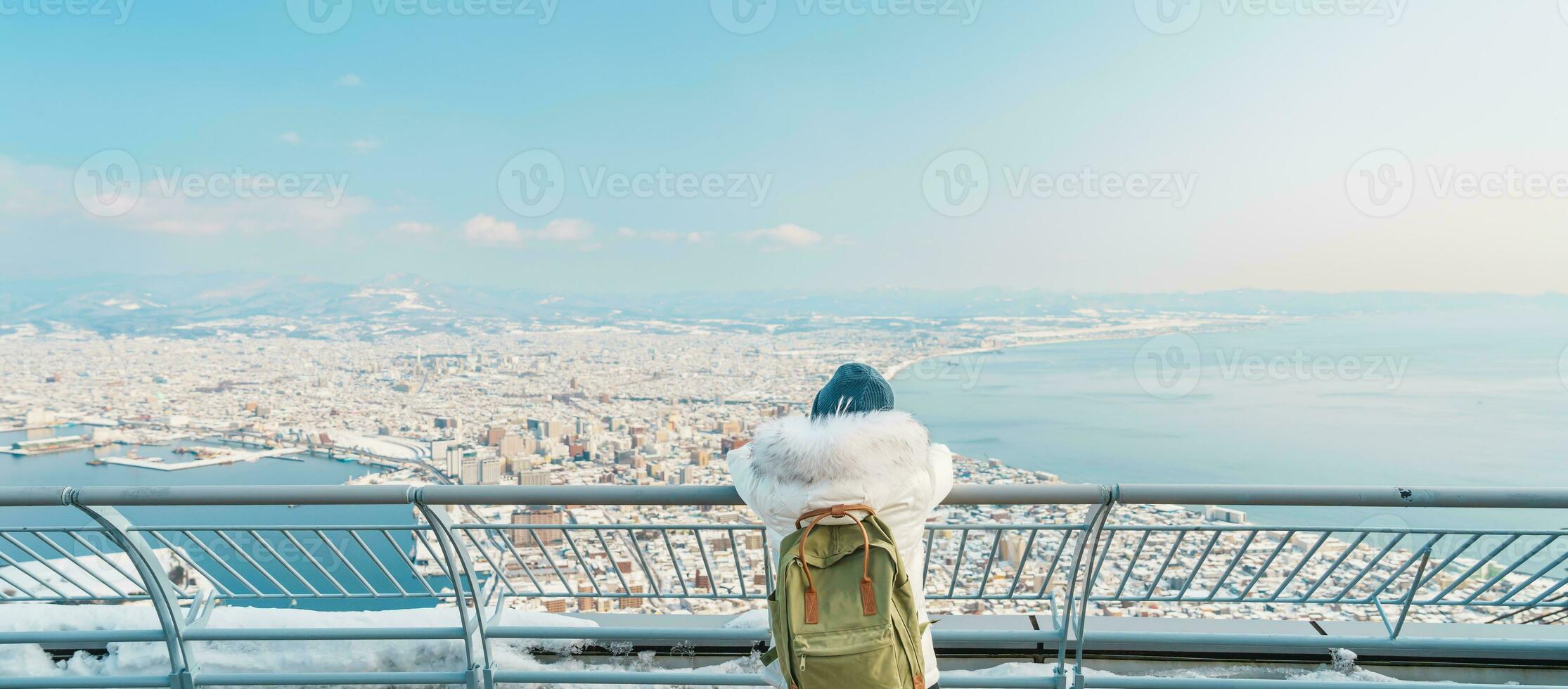 Woman tourist Visiting in Hakodate, Traveler in Sweater sightseeing view from Hakodate mountain with Snow in winter. landmark and popular for attractions in Hokkaido, Japan.Travel and Vacation concept photo