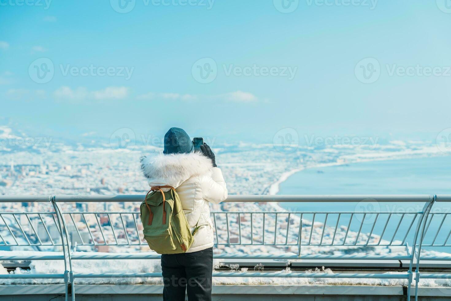Woman tourist Visiting in Hakodate, Traveler in Sweater sightseeing view from Hakodate mountain with Snow in winter. landmark and popular for attractions in Hokkaido, Japan.Travel and Vacation concept photo