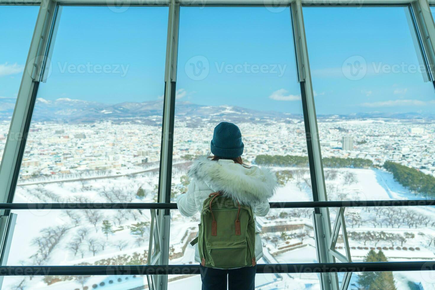 Woman tourist Visiting in Hakodate, Traveler in Sweater sightseeing view from Goryokaku Tower with Snow in winter. landmark and popular for attractions in Hokkaido, Japan.Travel and Vacation concept photo