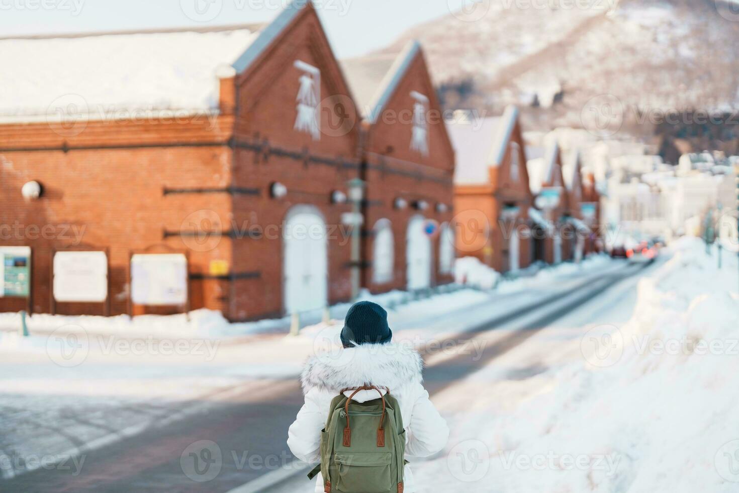 Woman tourist Visiting in Hakodate, Traveler in Sweater sightseeing Kanemori Red Brick Warehouse with Snow in winter. landmark and popular for attractions in Hokkaido,Japan.Travel and Vacation concept photo