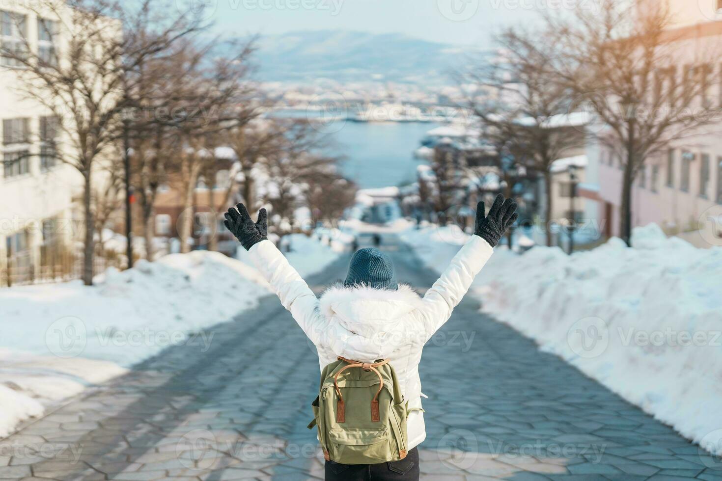 Woman tourist Visiting in Hakodate, Traveler in Sweater sightseeing Hachiman Zaka Slope with Snow in winter. landmark and popular for attractions in Hokkaido, Japan. Travel and Vacation concept photo