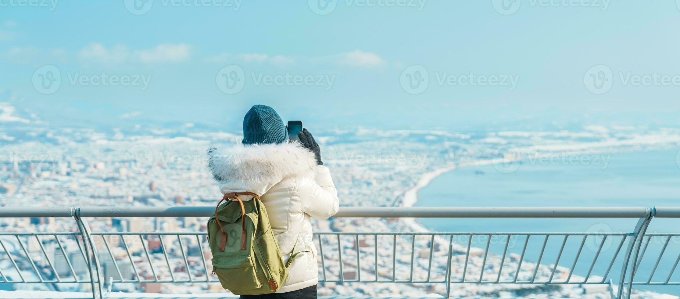 Woman tourist Visiting in Hakodate, Traveler in Sweater sightseeing view from Hakodate mountain with Snow in winter. landmark and popular for attractions in Hokkaido, Japan.Travel and Vacation concept photo