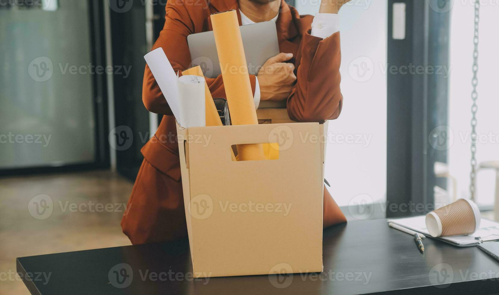 Business man employee stressful resignation from job while picking up personal belongings into brown cardboard box and carrying to walking out from office photo