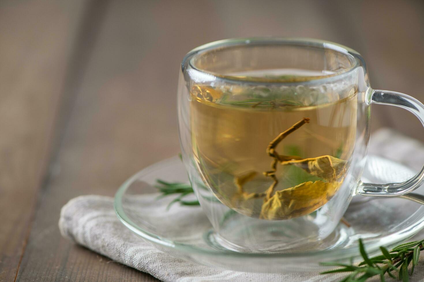 caliente té en madera mesa. transparente taza de recién elaborada té en madera mesa foto