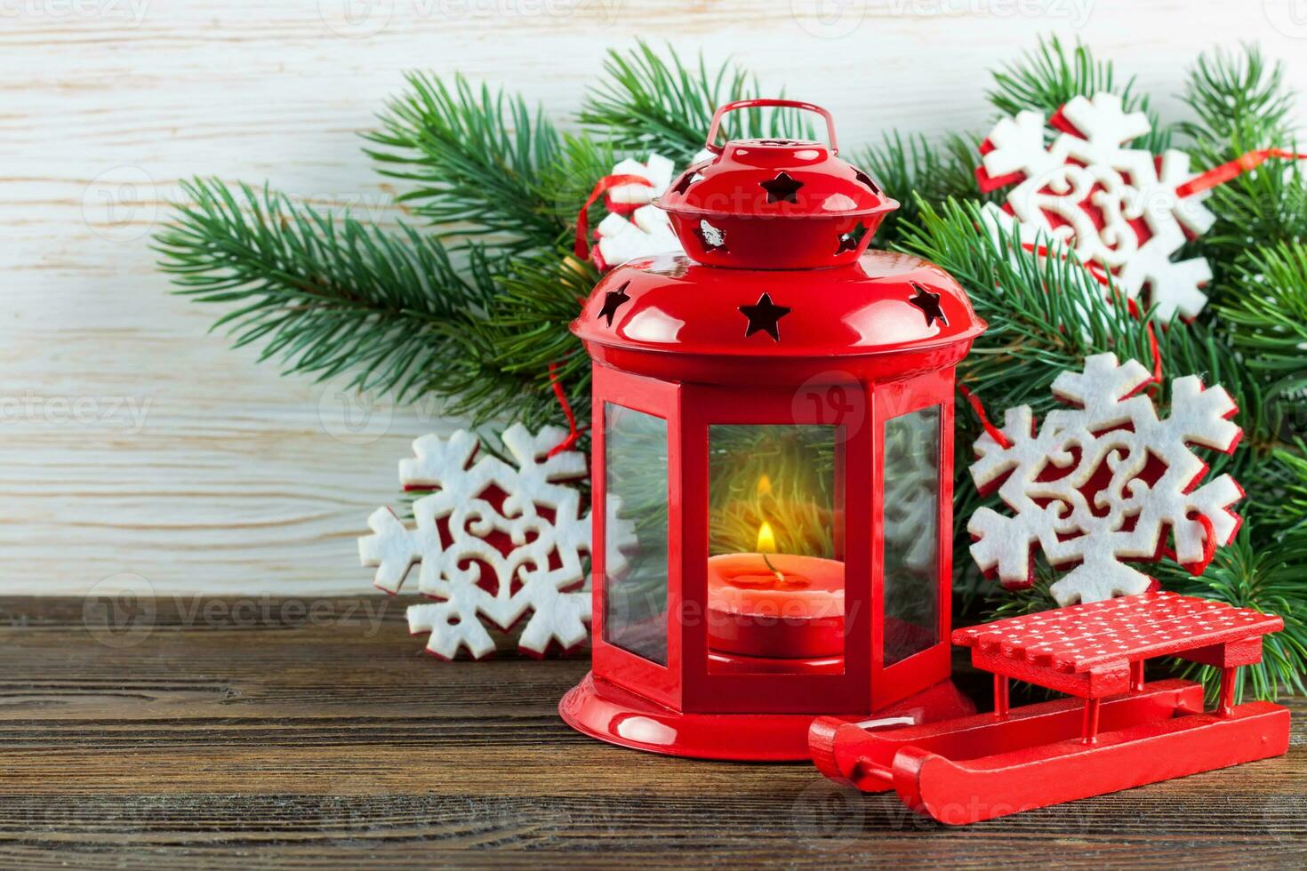 Lantern and Christmas tree over snow on wooden background photo