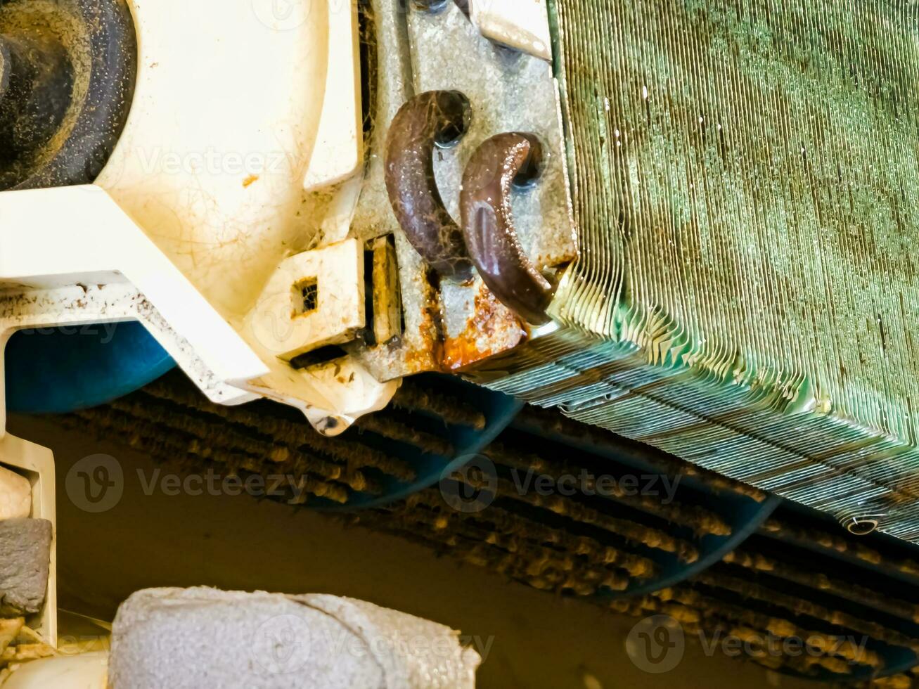 Radiator of the indoor unit of an old dirty air conditioner close-up with copper tubes and plates and water drops on it. photo