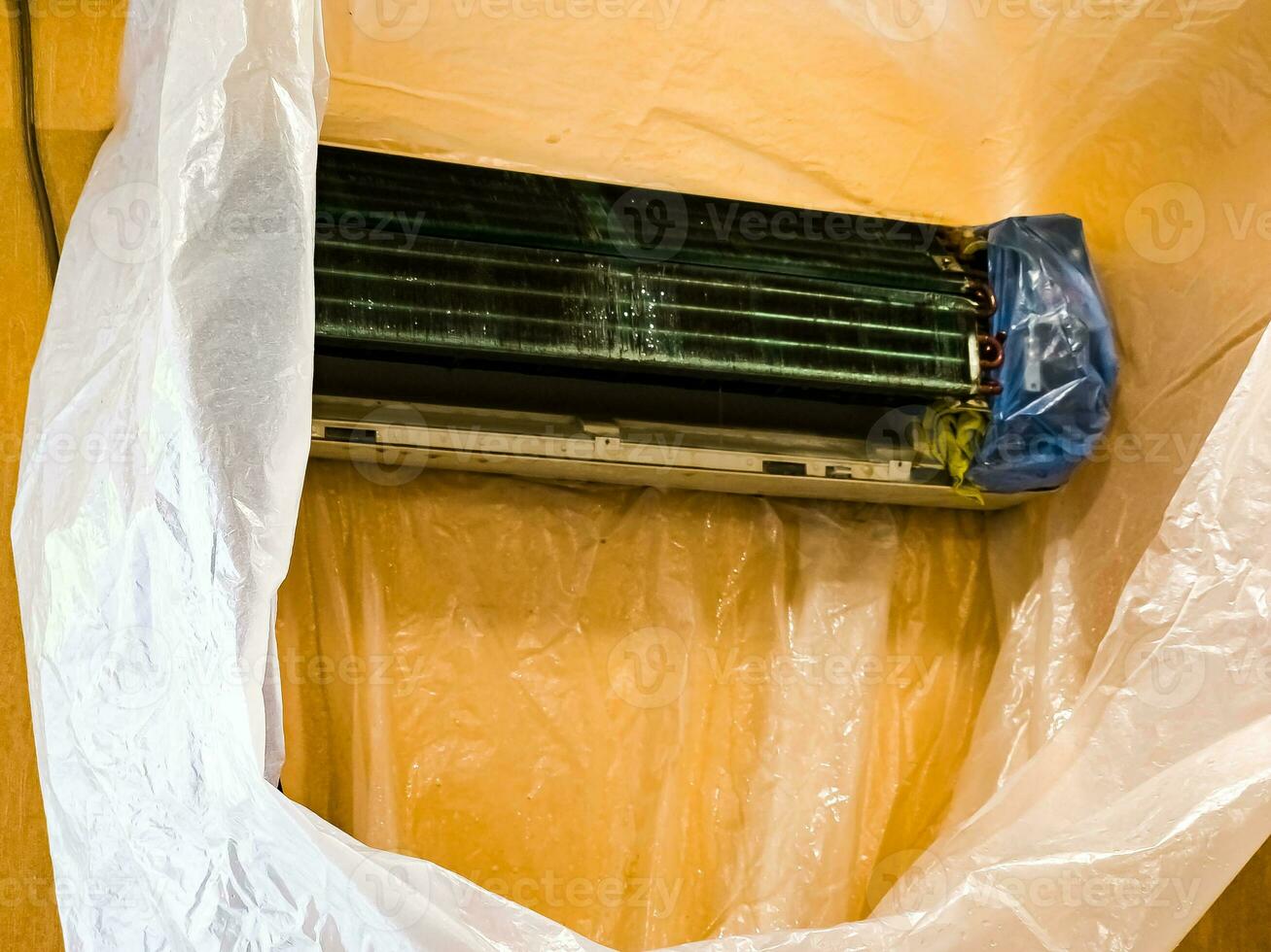 Preparing for cleaning the indoor unit of the air conditioner and wrapping it in a polyethylene sleeve. Cleaning with water jet and chemicals. photo