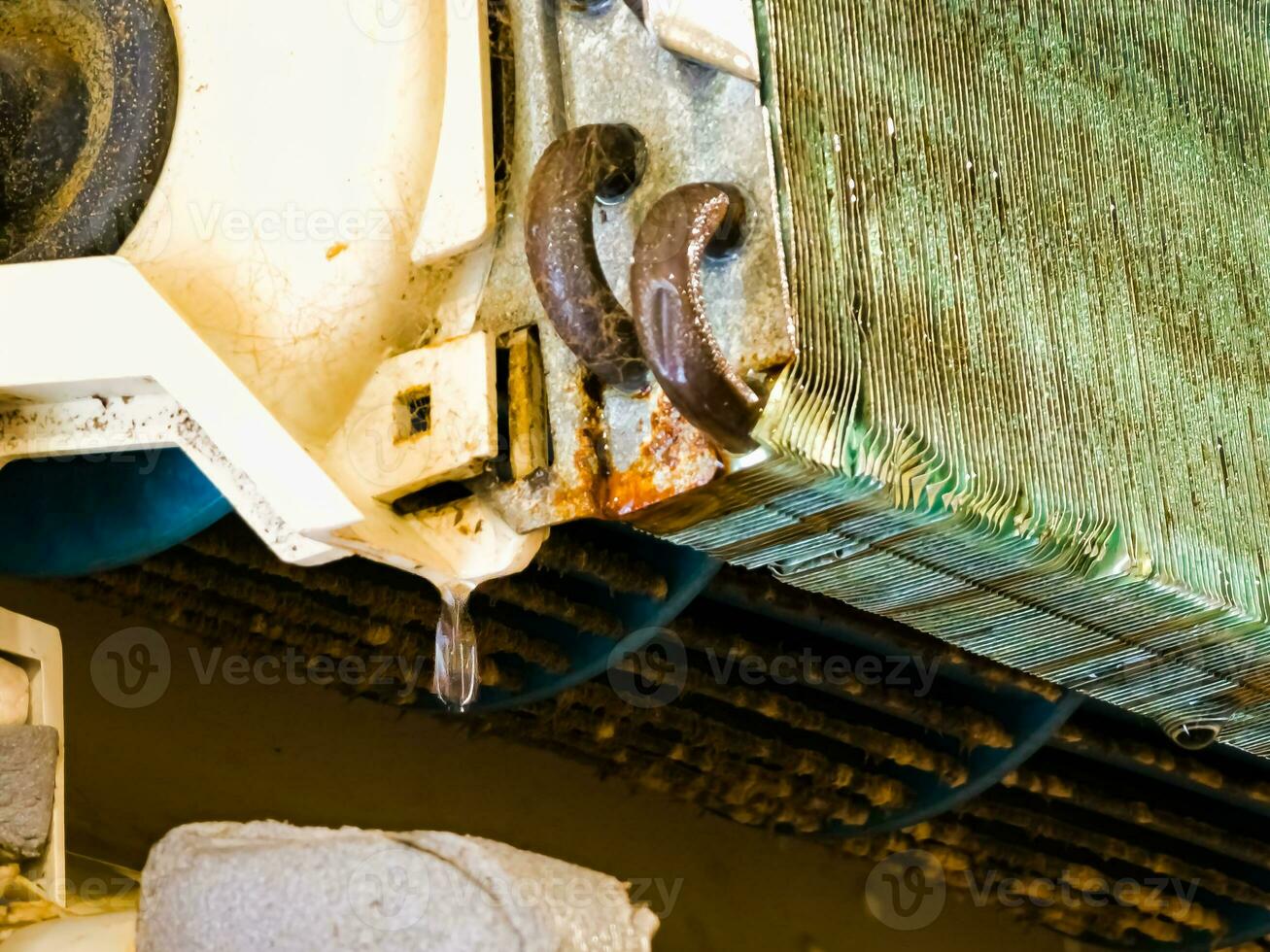 Radiator of the indoor unit of an old dirty air conditioner close-up with copper tubes and plates and water drops on it. photo