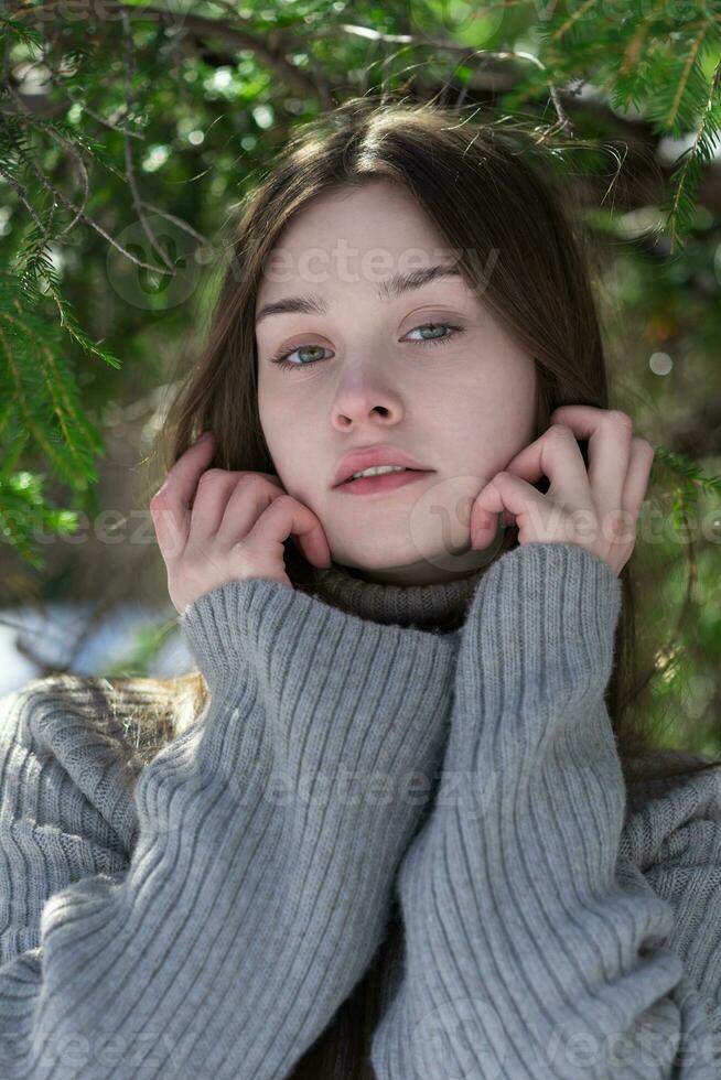 disparo a la cabeza de adolescente niña mirando a cámara, elevado manos a rostro, vistiendo gris suéter foto