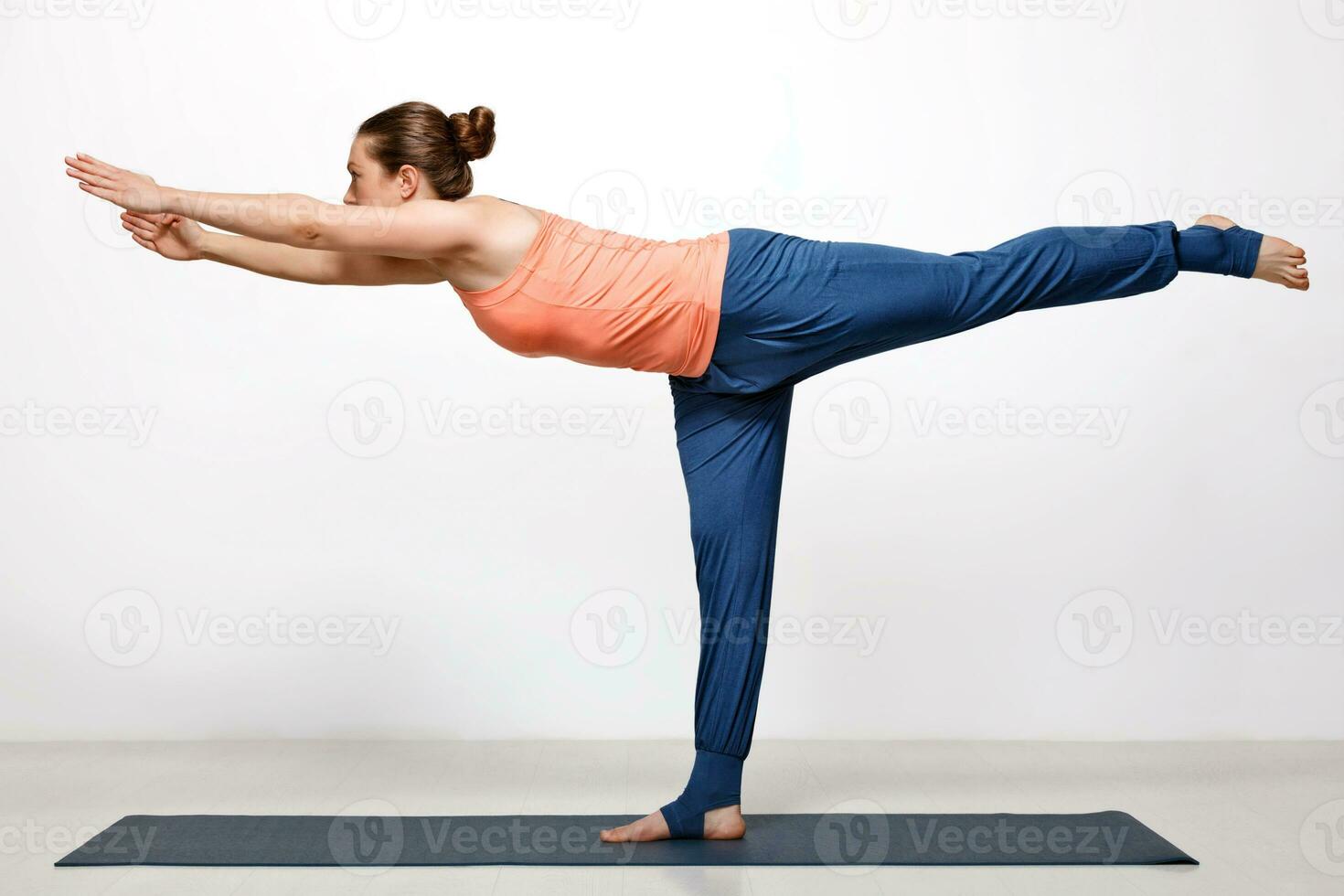 Woman practices yoga asana utthita Virabhadrasana photo