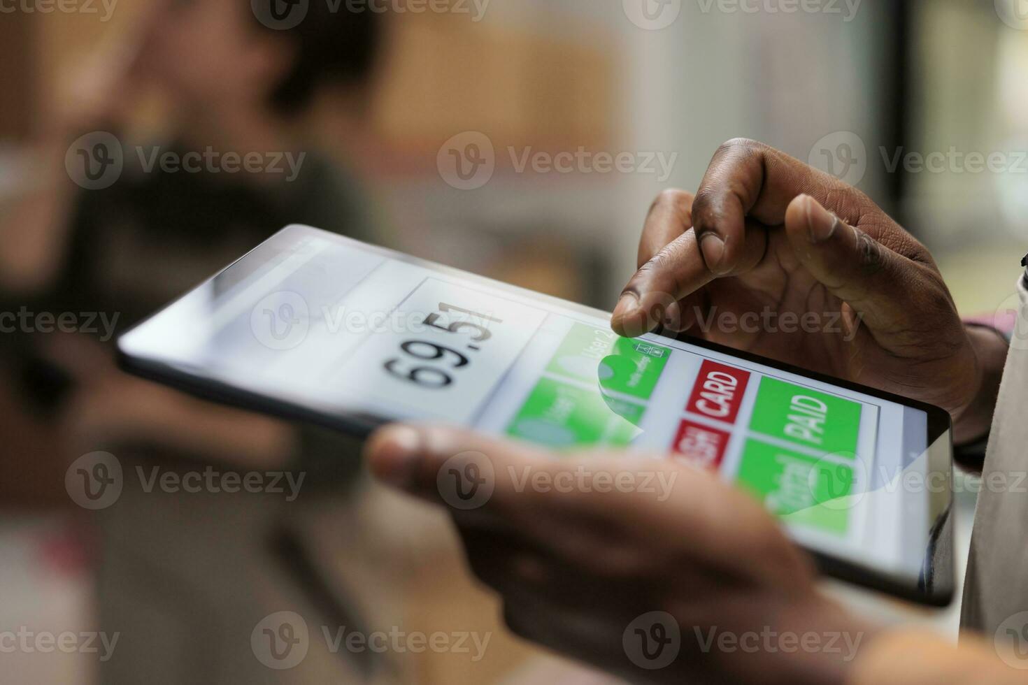 Employee analyzing customers online orders using tablet computer, preparing cardboard boxes for delivery. African american storage room supervisor working at products inventory in warehouse. Close up photo