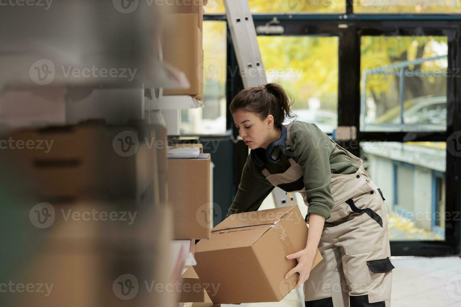 pequeño negocio trabajador en protector en general trabajando en almacenamiento habitación, que lleva caja de cartón cajas durante almacén inventario, supervisor preparando clientela pedidos antes de entrega productos almacén concepto foto