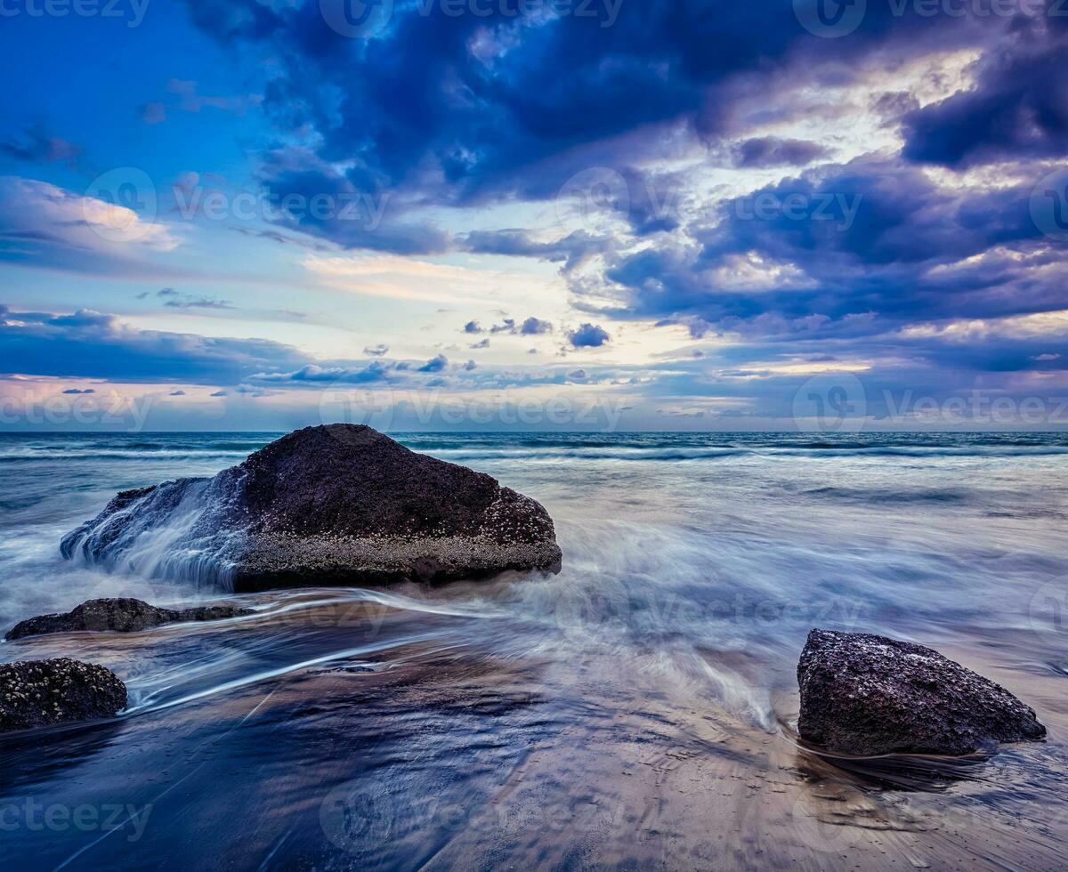 olas y rocas en la playa del atardecer foto